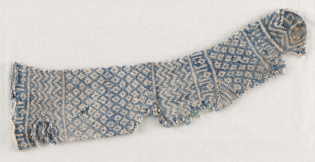 Another old tattered blue and white sock with geometric designs and stylized Kufic script.